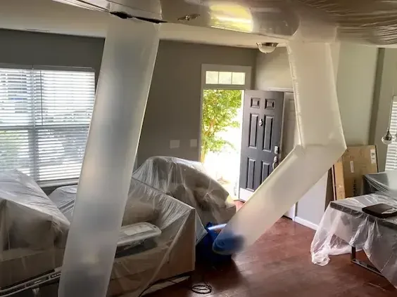 Drying ducts running past furniture wrapped in plastic during a dry-out